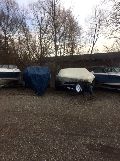 Covered boats on trailers parked in a row at the lot